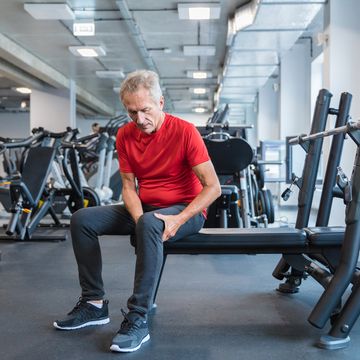 senior man suffering from knee pain at gym