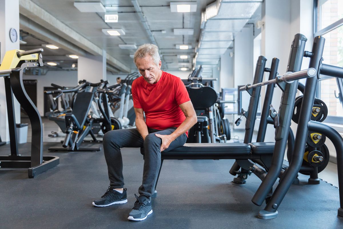 senior man suffering from knee pain at gym