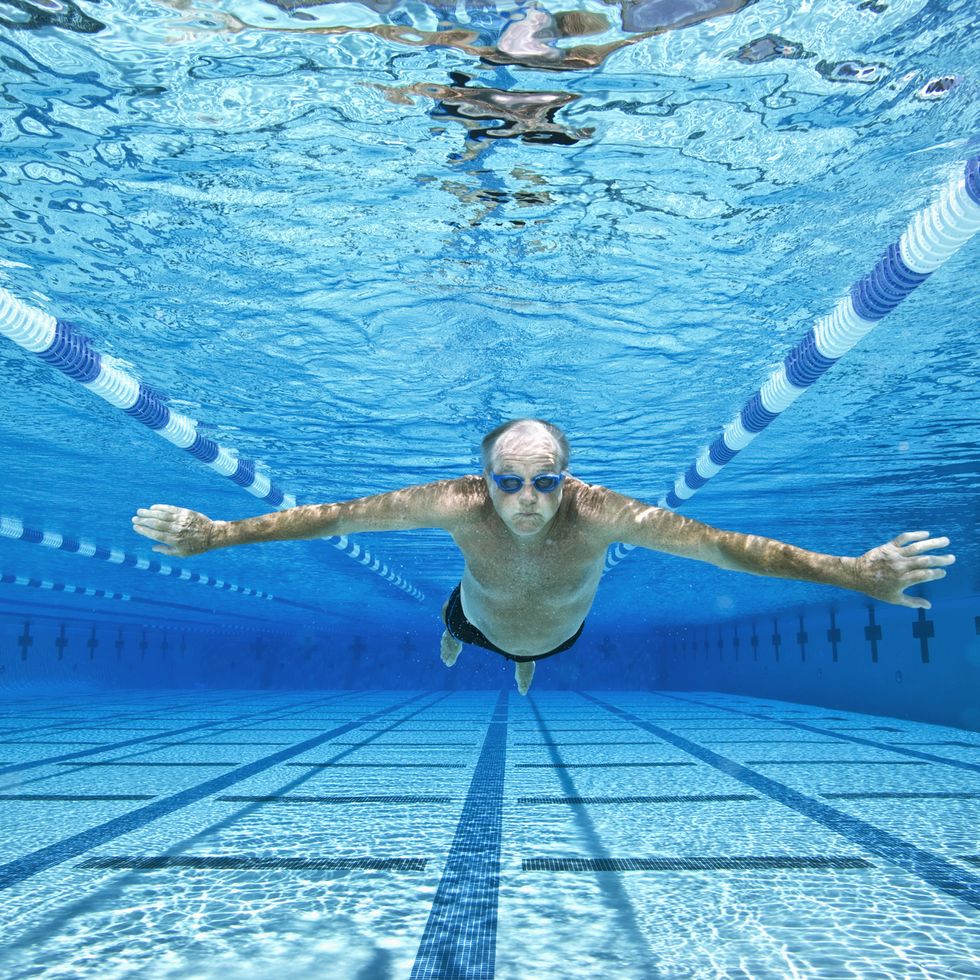 senior man swimming in pool, underwater view