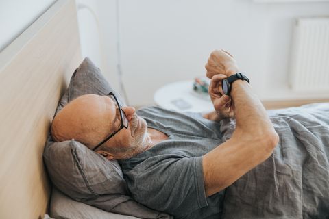 man using smartwatch in bed