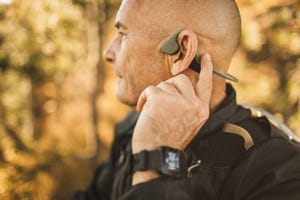 senior man wearing bone conduction headphones to listen music on forest walk or hike close up