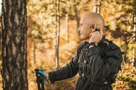 senior man wearing bone conduction headphones to listen music on forest walk or hike