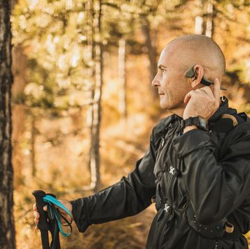 senior man wearing bone conduction headphones to listen music on forest walk or hike