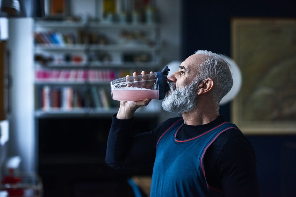 senior man wearing sports top gulping health drink from container