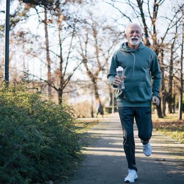 senior man who enjoys being outdoors, in nature, on a lovely autumn day and jogging