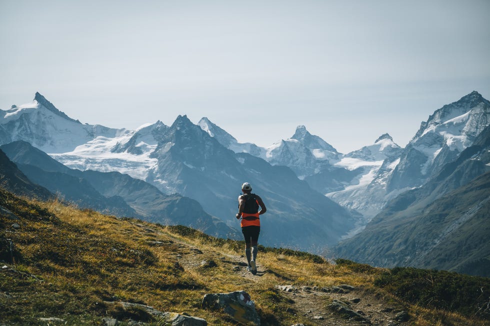 senior mountain trail runner ascends alpine ridge trail