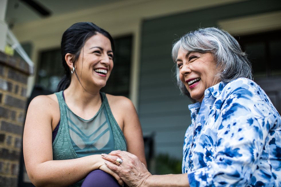 senior woman and adult daughter laughing on porch