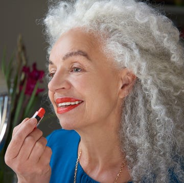 woman applying lipstick in mirror makeup tips