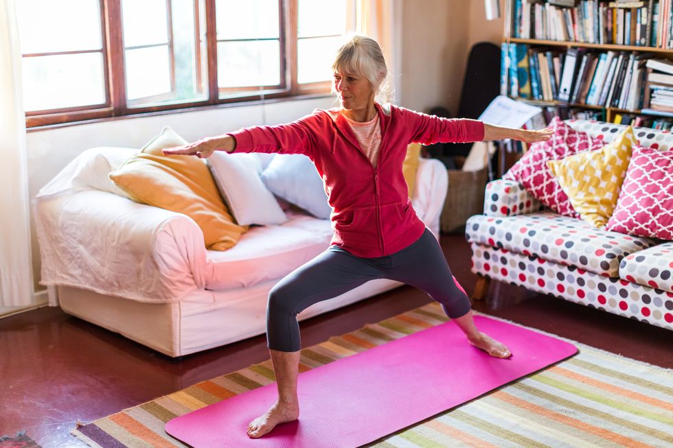 senior woman doing yoga in the living room of her home
