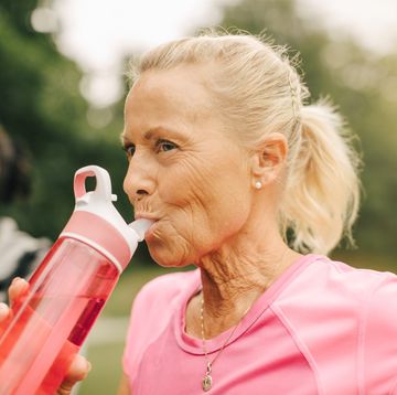 senior woman drinking water from bottle in park