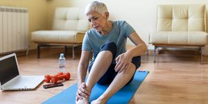 senior woman has ankle injury on yoga mat