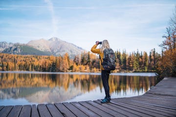 a senior woman hiker in autumn nature, using binoculars