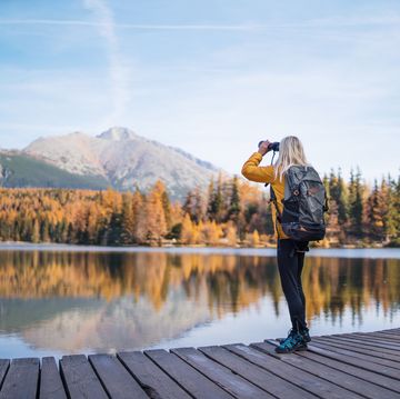 a senior woman hiker in autumn nature, using binoculars