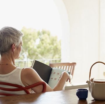 senior woman holding book while siting on chair