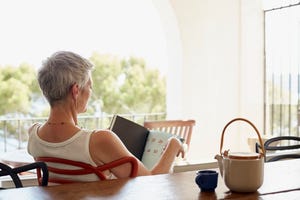 senior woman holding book while siting on chair