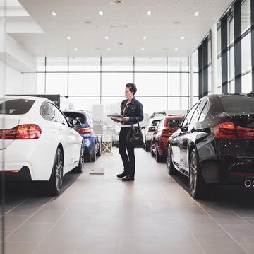 senior woman holding documents and looking at cars in showroom