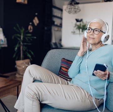 senior woman listening to a podcast at her living room