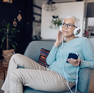 senior woman listening to a podcast at her living room