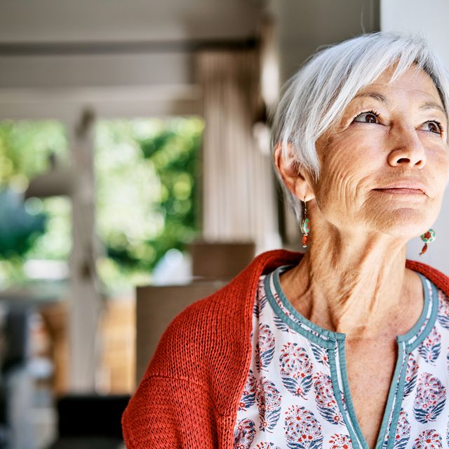 senior woman lost in thought while standing alone at home