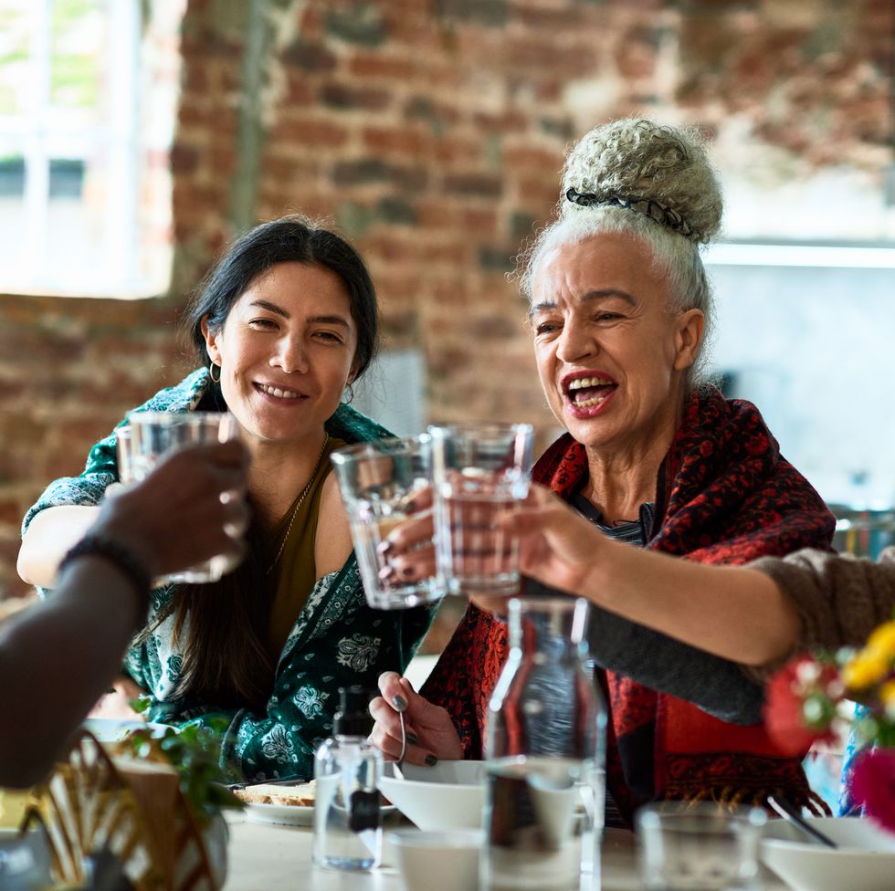 senior woman raising glass of water with friends