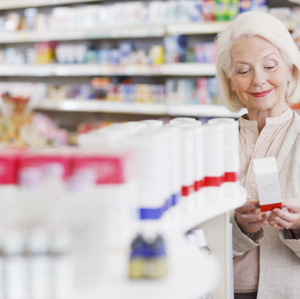 senior woman reading package in drug store