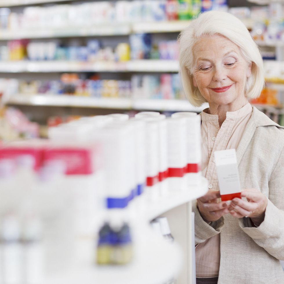 senior woman reading package in drug store
