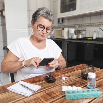 senior woman recording her blood sugar level with a smartphone