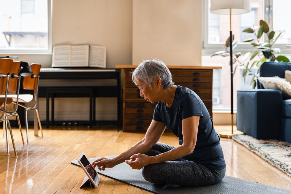 woman using digital tablet while exercising in living room