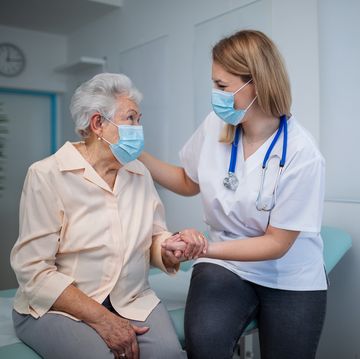 senior woman with female doctor wearing protective face masks and talking warmly in doctors office