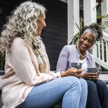 senior women having coffee in front of suburban home
