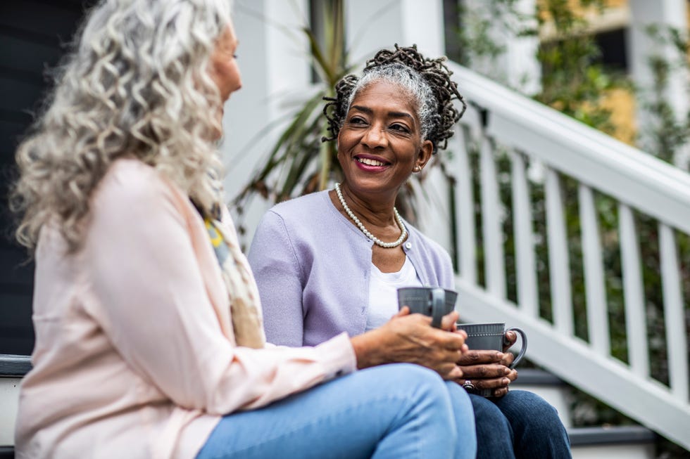 senior women having coffee in front of suburban home