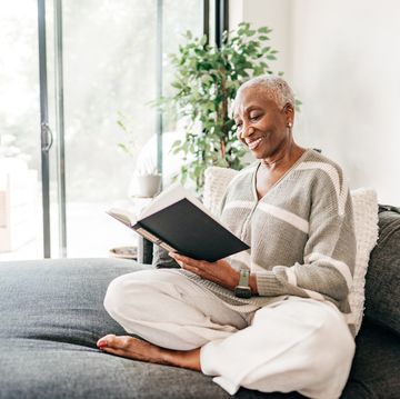 senior women sitting on sofa and reading a book at home