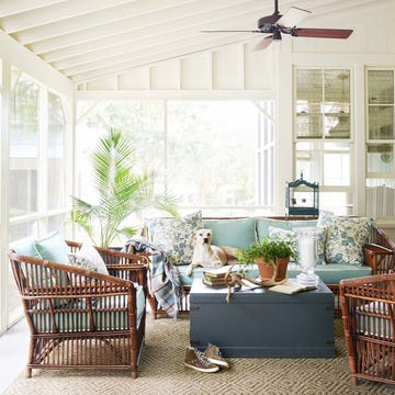 a screened porch with a fan with rattan furniture