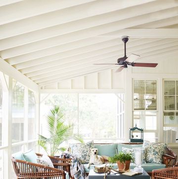 a screened porch with a fan with rattan furniture