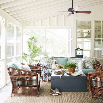 a screened porch with a fan with rattan furniture