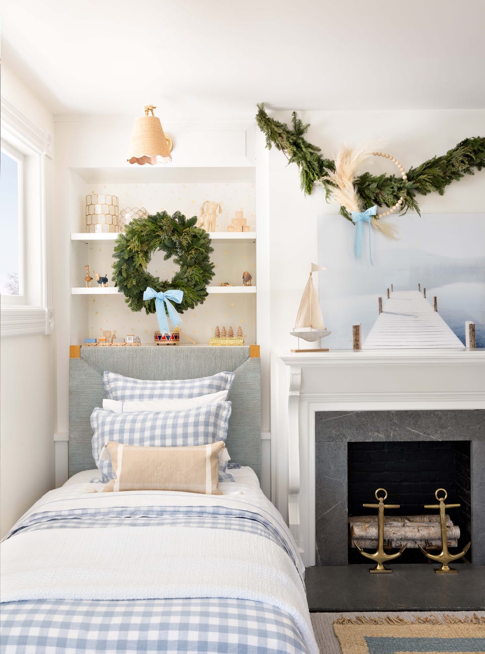 small twin bed next to fireplace and underneath a simple green wreath