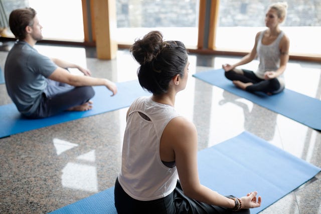 Serene people practicing yoga, sitting in lotus position in studio