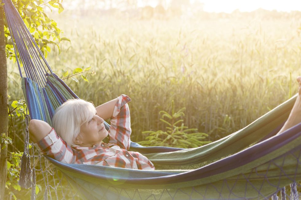 serene senior woman laying in hammock next to rural wheat field