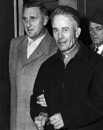 serial killer ed gein in handcuffs as two men walk behind