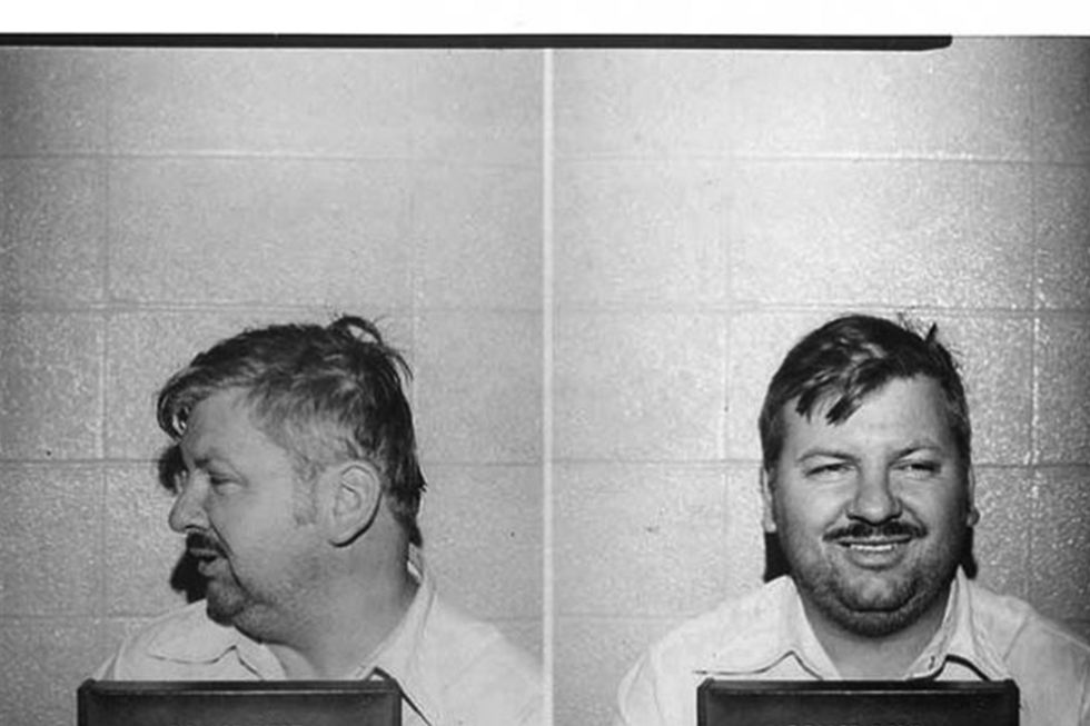 two black and white photos of john wayne gacy holding a sign that says police dept des plaines, ill, with gacy looking straight ahead and smiling in one, and looking to the side in the other