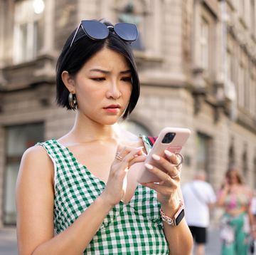 woman out on city sidewalk looking concerned at her smartphone
