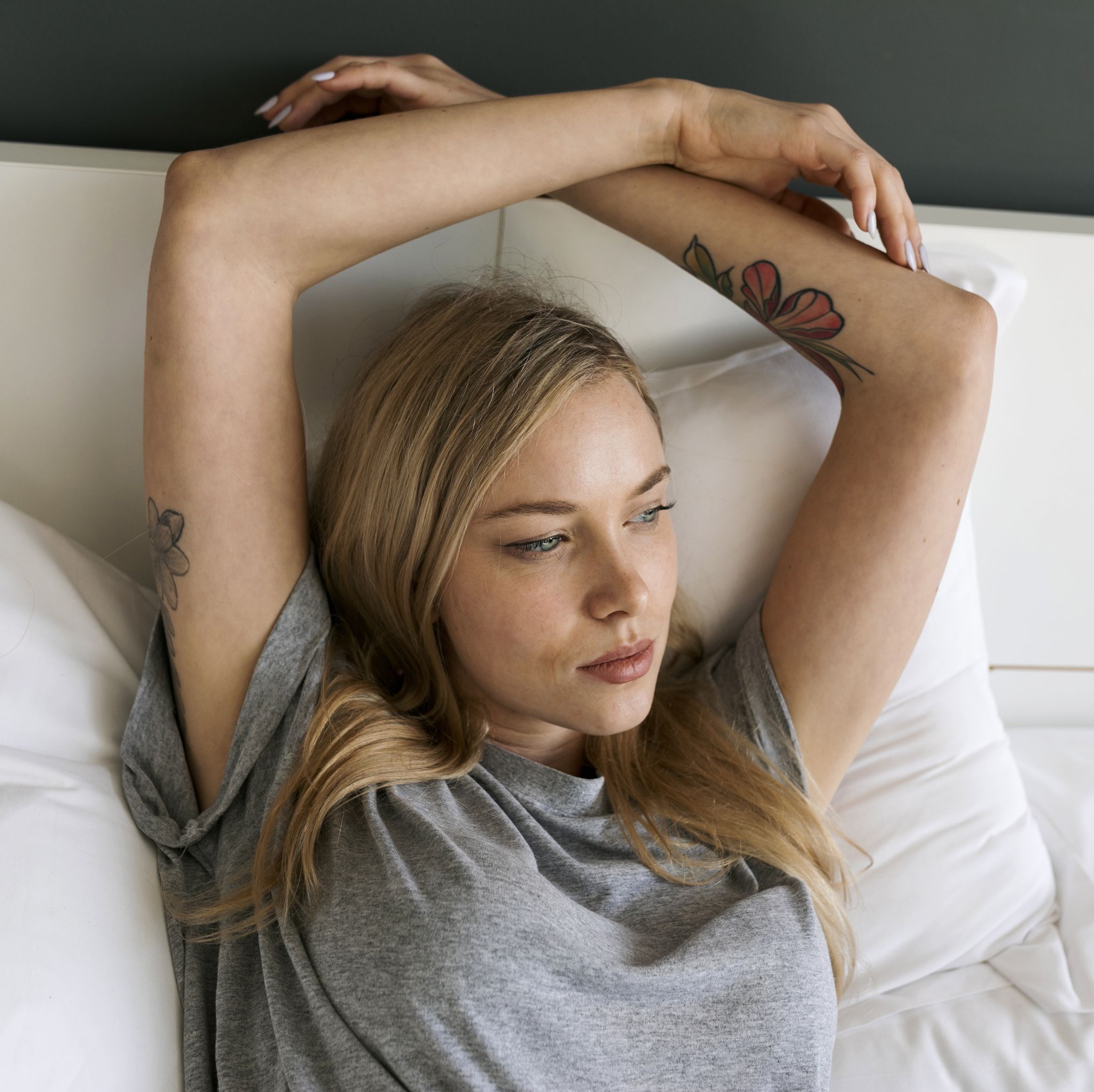Serious blond young woman lying in bed