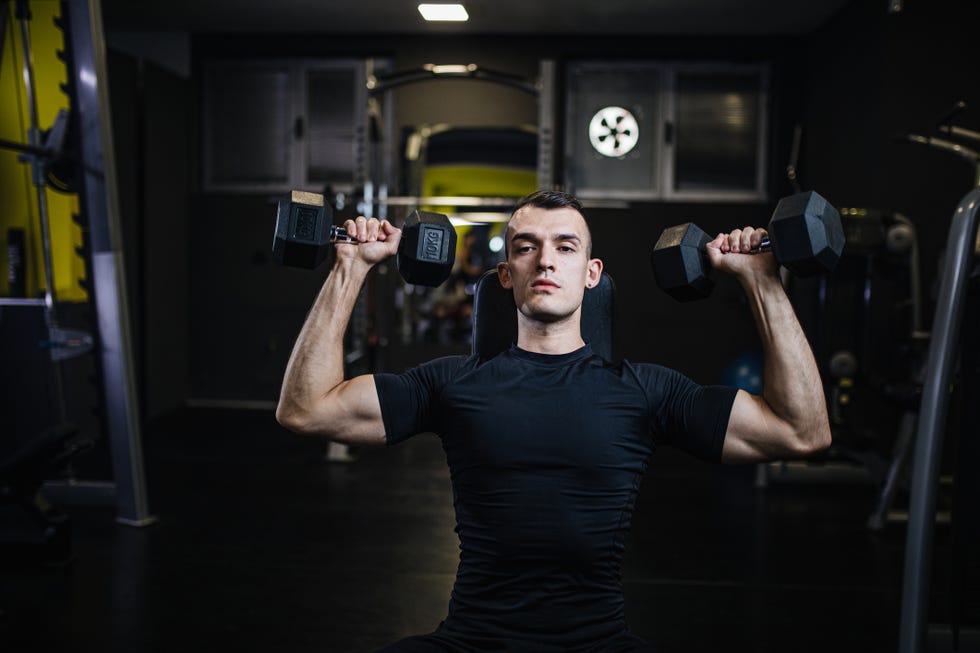 serious man training upper body using dumbbells