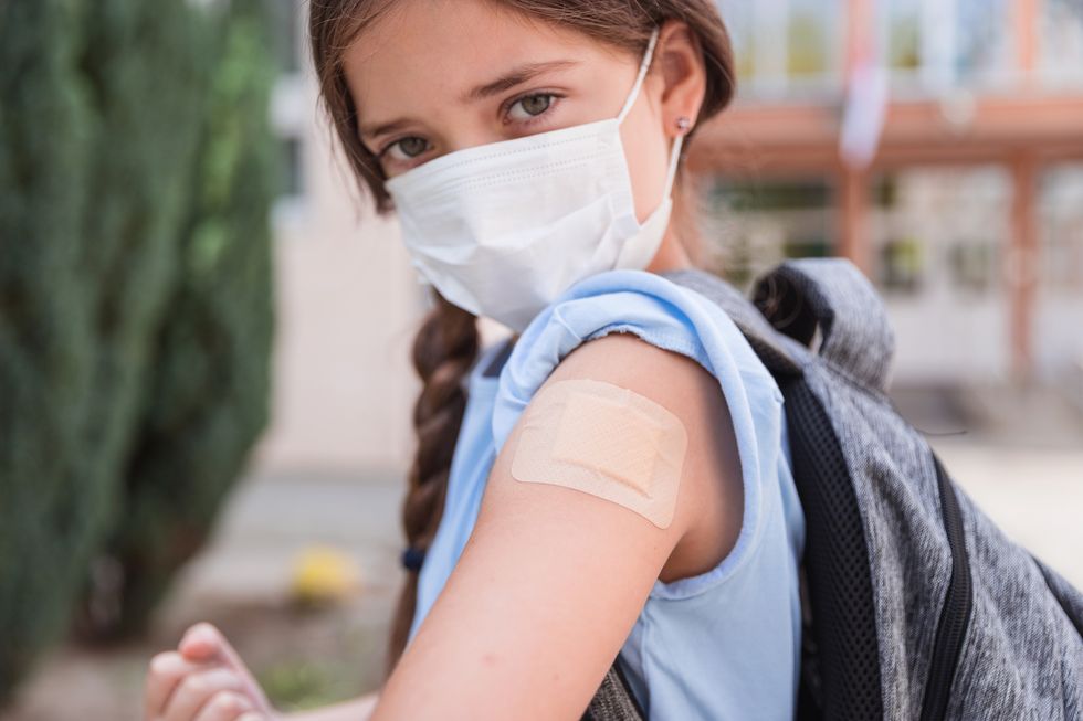 serious school girl wearing a bandage on the vaccine spot