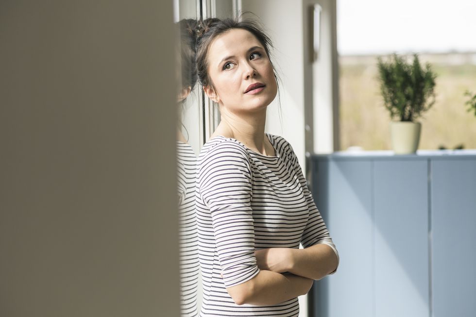 serious woman looking out of window at home