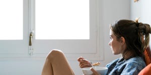 serious young woman eating cereals in bed