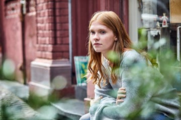 serious young woman sitting at house entrance