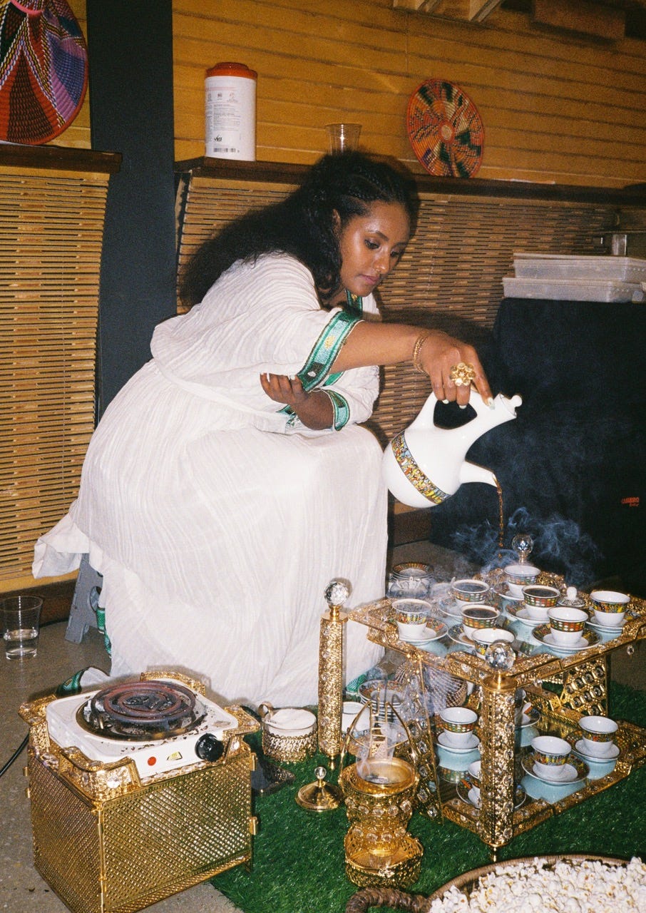 a person in a white dress pouring coffee for an ethiopian coffee ceremony