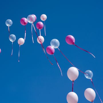 set of clear and pink balloons flying up the blue sky