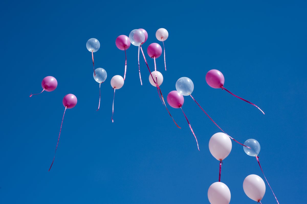 set of clear and pink balloons flying up the blue sky